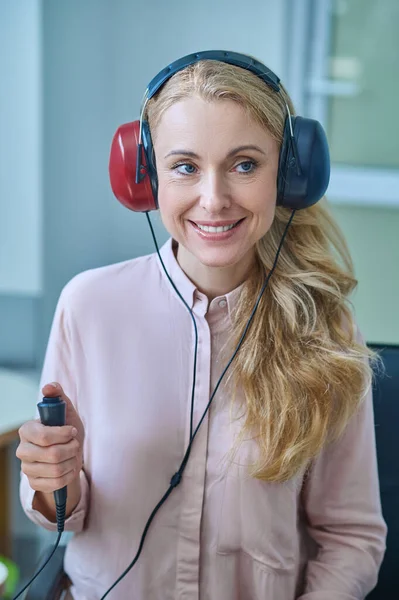 Усміхнена жінка в спеціальних навушниках перевіряє її слух — стокове фото