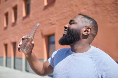 Sokakta yürüyen beyaz tişörtlü esmer bir adam.