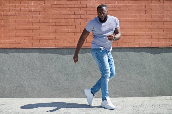 Un hombre de piel oscura con una camiseta blanca y jeans sintiéndose bien —  Fotos de Stock