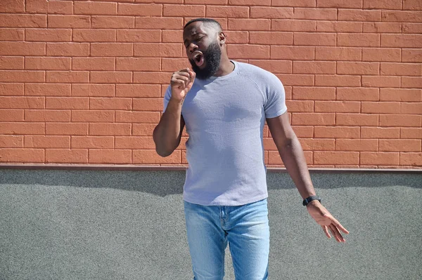 Un hombre de piel oscura con una camiseta blanca y jeans sintiéndose bien —  Fotos de Stock