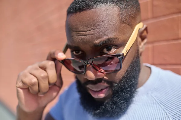 Un hombre de piel oscura con una camiseta blanca y gafas de sol que parecen seguras — Foto de Stock