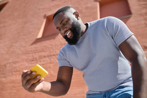 Un hombre de piel oscura con una camiseta blanca haciendo selfie — Foto de Stock