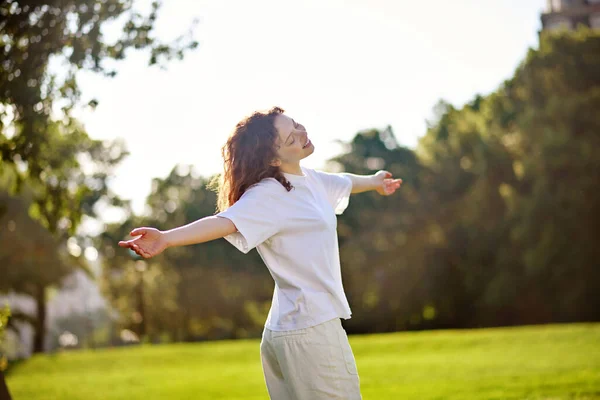 Una chica pelirroja de pelo largo que pasa tiempo en un parque sintiéndose feliz —  Fotos de Stock