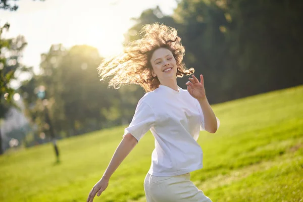 Ein langhaariges Mädchen mit Ingwer verbringt Zeit in einem Park und fühlt sich glücklich — Stockfoto