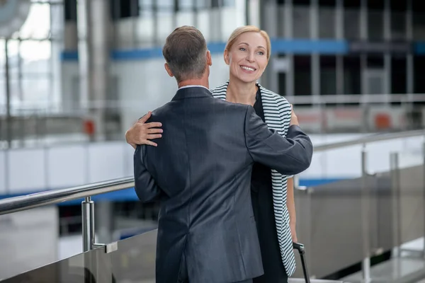 Άντρας αγκαλιάζει γυναίκα με βαλίτσα στο αεροδρόμιο — Φωτογραφία Αρχείου