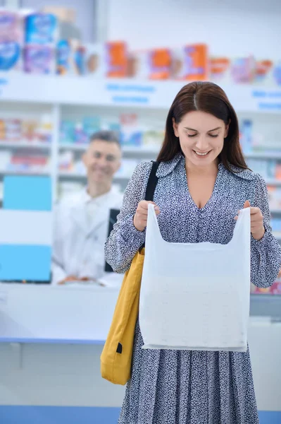 Glimlachende vrouw kijkt naar pakket met aankoop — Stockfoto