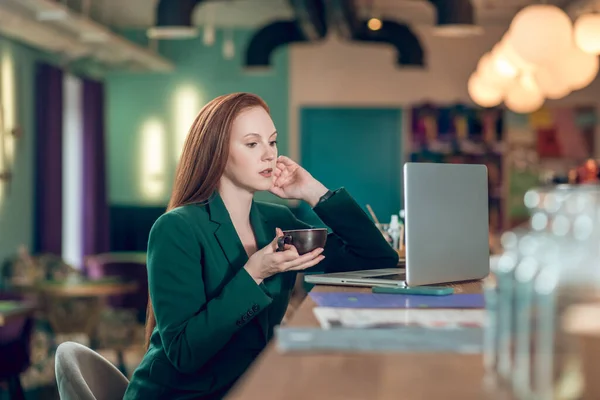 Mujer bebiendo café frente a la computadora portátil en la cafetería —  Fotos de Stock