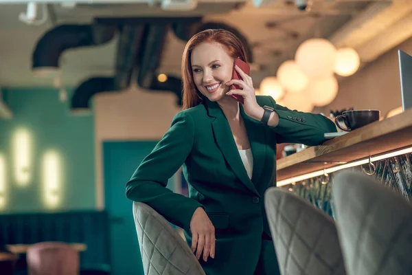 Mulher sorridente falando no smartphone no café — Fotografia de Stock