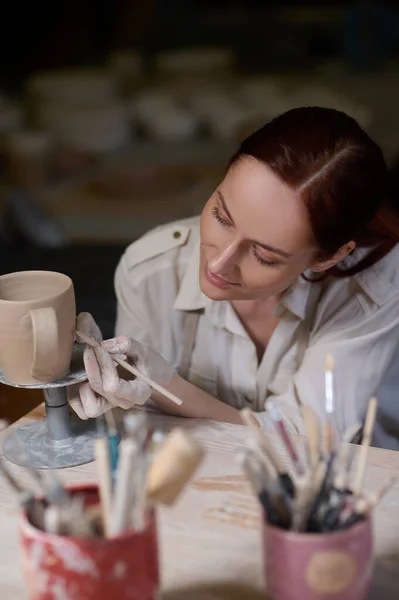 A young woman painting the pottery and looking involved — Stock Photo, Image