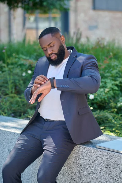 Un hombre de piel oscura con un traje mirando el reloj — Foto de Stock