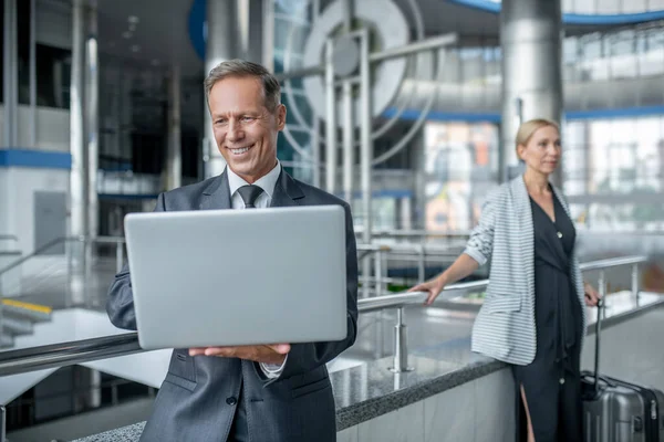 Glimlachende zakenman op zoek naar laptop en collega — Stockfoto