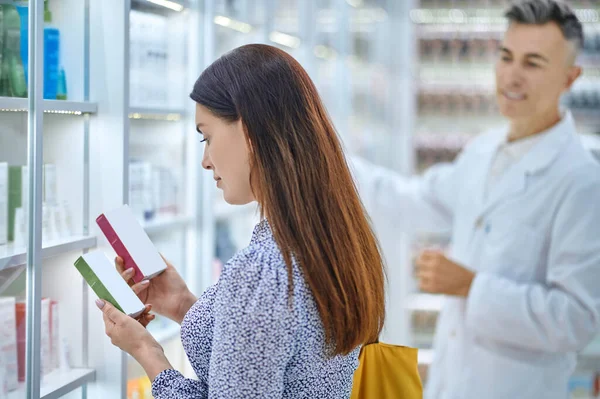 Mujer con dos paquetes de medicina y el hombre detrás —  Fotos de Stock