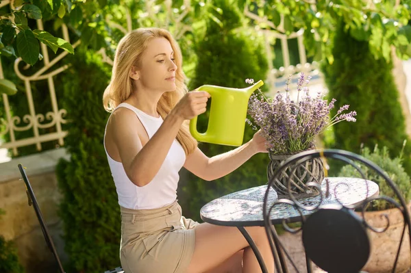 Pensive vrouw met gieter in de buurt van bloempot — Stockfoto