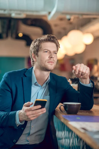 Hombre melancólico con smartphone y taza de café — Foto de Stock