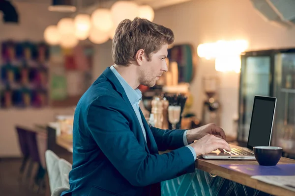 Perfil del hombre mirando en el ordenador portátil en la cafetería — Foto de Stock