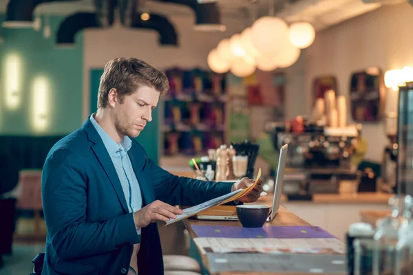 Serieuze man lezen document in map zitten in cafe — Stockfoto