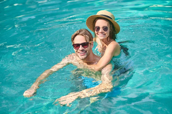 Havuzda yüzen mutlu genç bir çift.