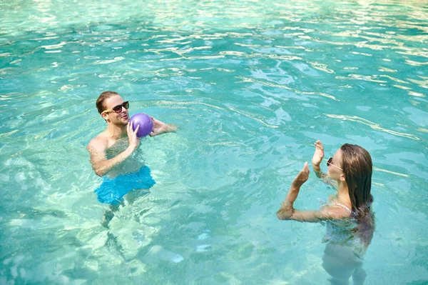 A man and a womna playing ball in a swimming pool — Stock Photo, Image