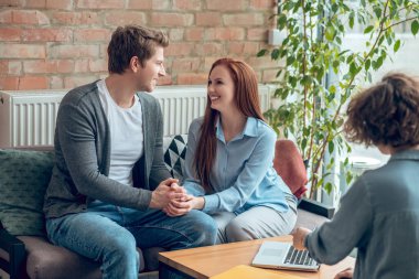 Komisyon ofisinde el ele tutuşan mutlu adam ve kadın.