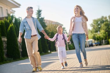 Sırt çantalı küçük kız ailesiyle yürüyor.