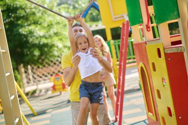 Baba ve kızı aktif olarak çocuk parkında vakit geçiriyorlar.