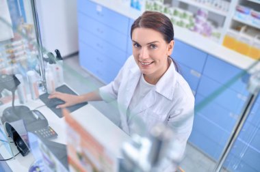 Kasanın arkasındaki neşeli kadın eczacı.