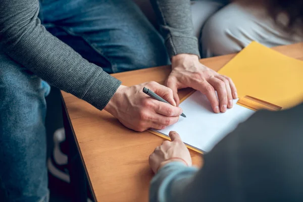 Männliche Hände unterzeichnen Dokument und Hand des Maklers — Stockfoto