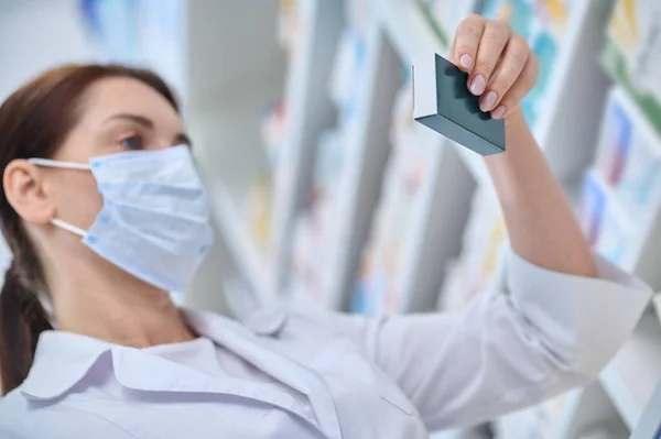薬剤師の女性は慎重に薬の包装を調べる — ストック写真