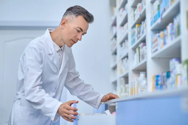Серьезный человек фармацевт открывает шкаф с лекарствами — стоковое фото