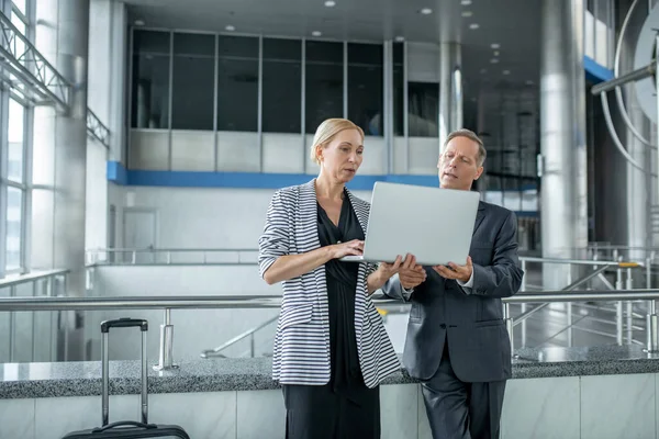 Ernstige vrouw en man op zoek naar laptop op de luchthaven — Stockfoto