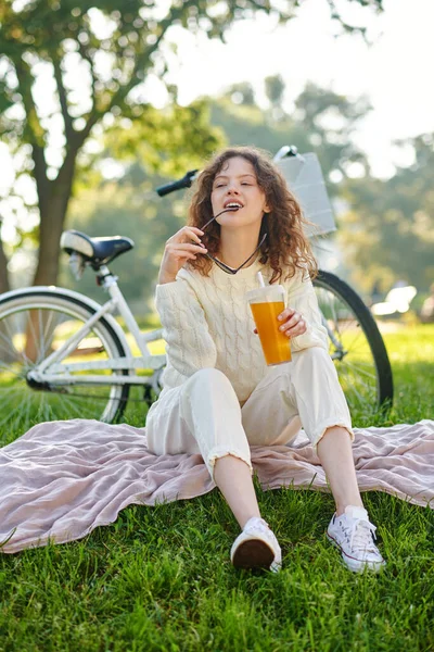 Una chica de blanco sentada en una hierba en el parque y mirando relajado —  Fotos de Stock