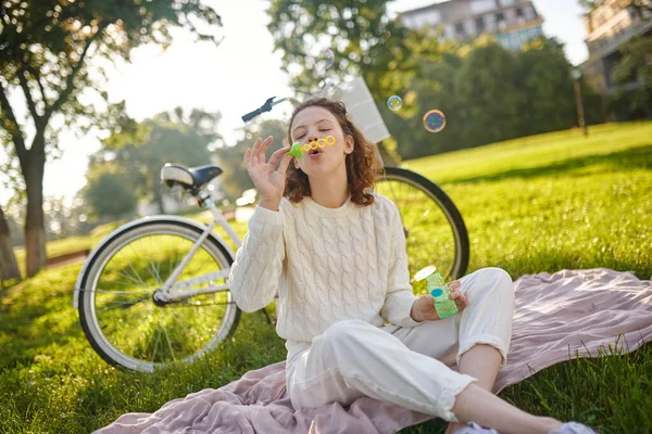 Una joven en blanco haciendo burbujas y buscando disfrutado — Foto de Stock