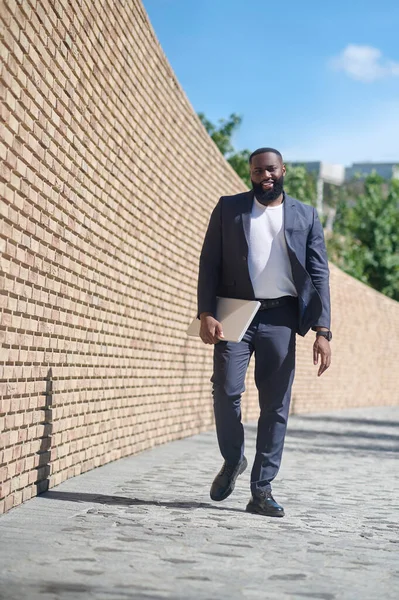 Koyu tenli bir adam tuğla duvarda yürüyor.