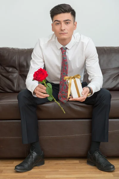 Businessman holding a flower and a present — Stock Photo, Image