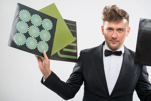 DJ in tuxedo showing his vinyl records standing by turntable — Stock Photo, Image