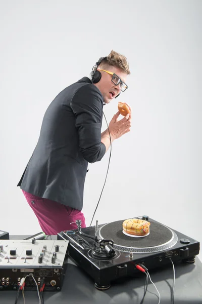 Dj eating donut on working place turntable — Stock Photo, Image