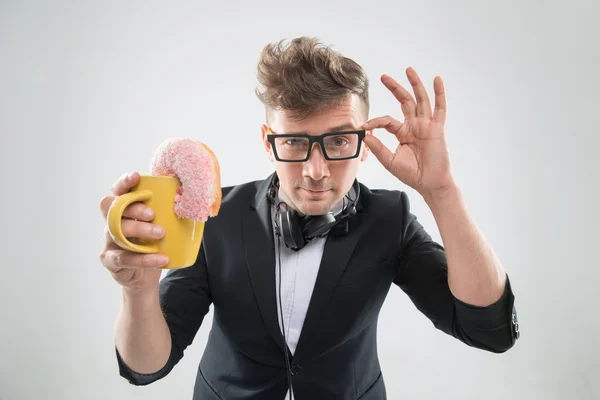 Dj handsome hipster eating donut from his cup on working place — Stock Photo, Image