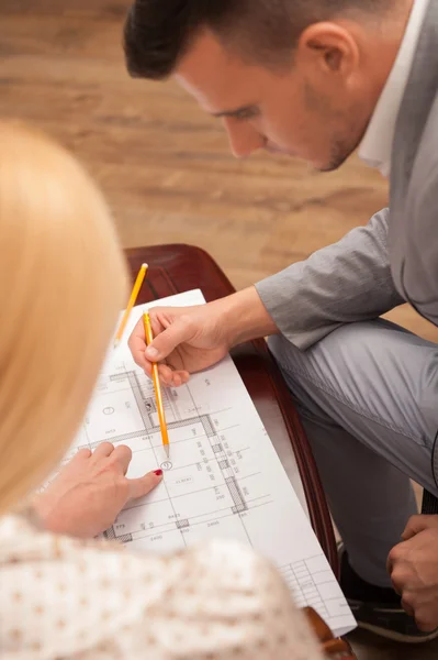 Young handsome architect discussing ground plan with client sitt — Stock Photo, Image