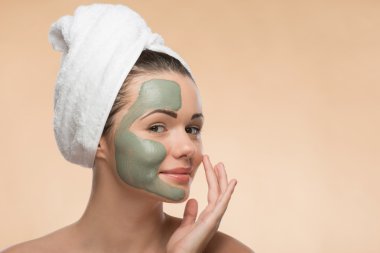 Spa kız yüz kil maskesi uygulayarak başında havlu ve