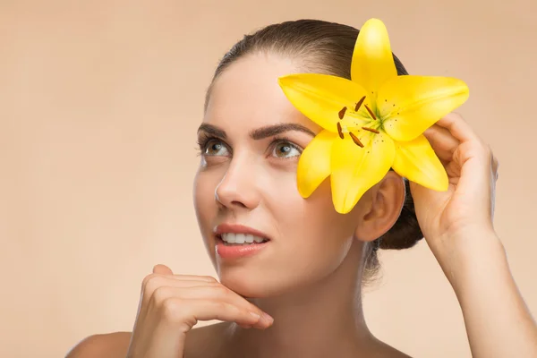 Menina bonita no spa com flor perto de seu rosto — Fotografia de Stock