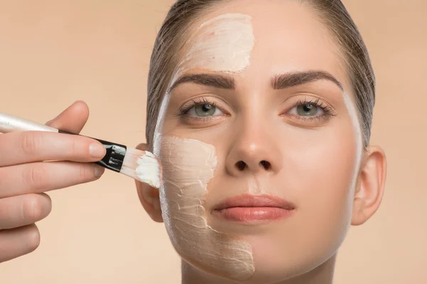 Hermosa chica en spa aplicando crema cosmética facial con cepillo —  Fotos de Stock