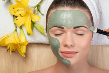 yüz kil mas uygulayarak başında bir havlu ile güzel kız