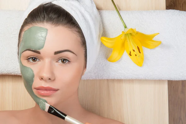 Beautiful girl with a towel on her head applying facial clay mas — Stock Photo, Image