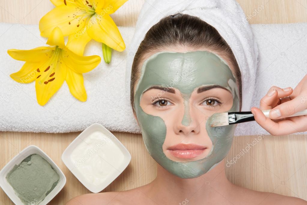 Girl applying facial cream mask
