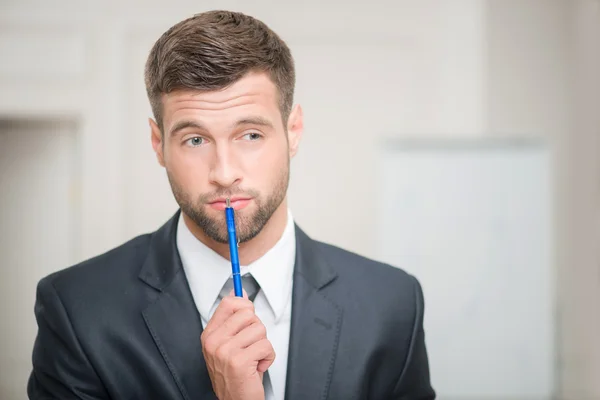 Empresário tocando seus lábios com uma caneta — Fotografia de Stock