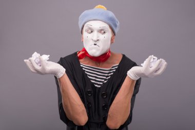 Male mime  holding crumped paper  and looking aside clipart