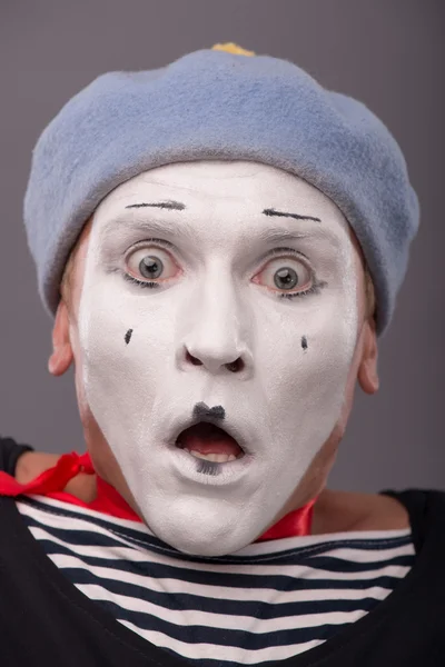 Portrait of young male mime with white face, grey hat showing em — Stock Photo, Image