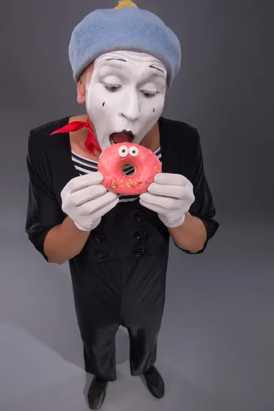 Ritratto di bel mimo maschile che mangia una gustosa ciambella rosa con fu — Foto Stock