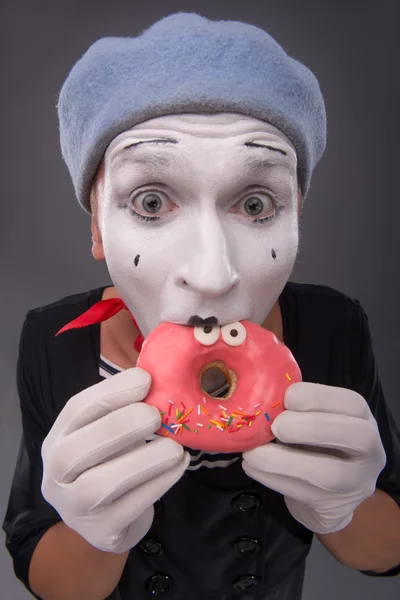 Portrait de beau mime masculin mangeant un délicieux beignet rose avec fu — Photo