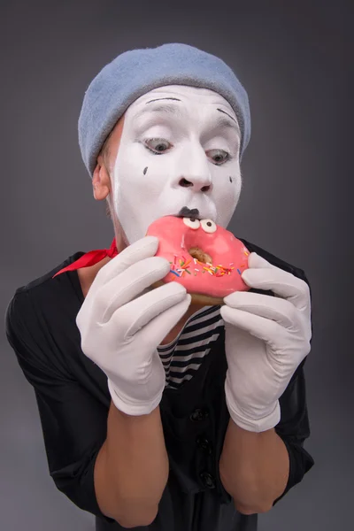 Porträt eines hübschen männlichen Mimen, der einen leckeren rosa Donut mit Fu isst — Stockfoto
